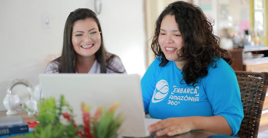a couple of women smiling at a laptop