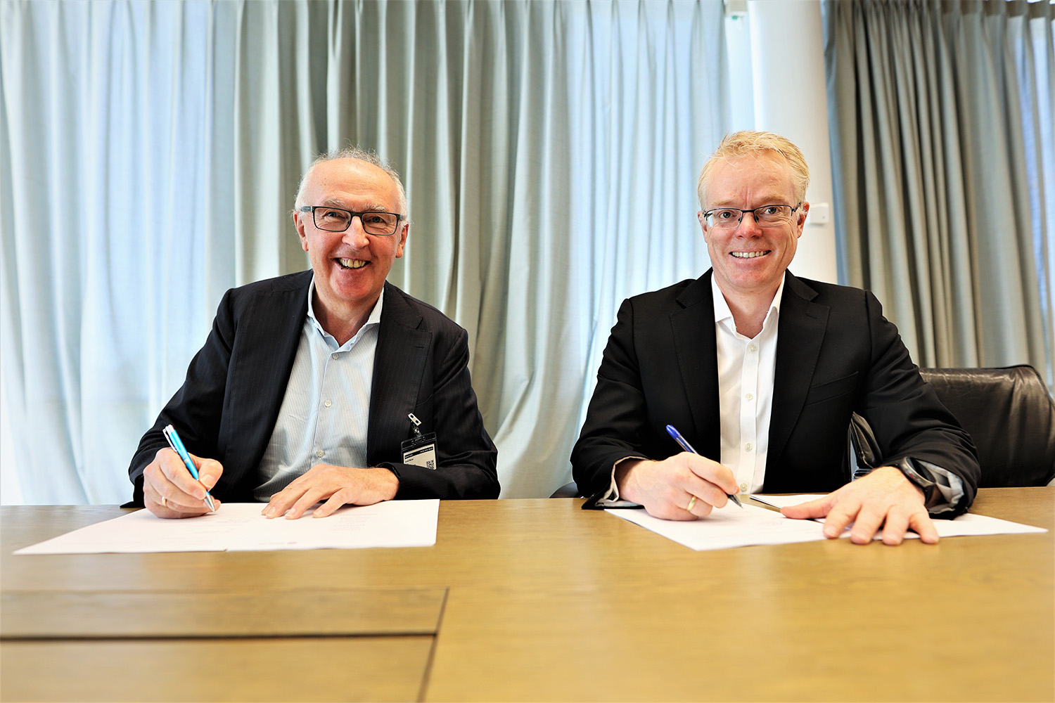 a couple of men sitting at a table with papers and pens