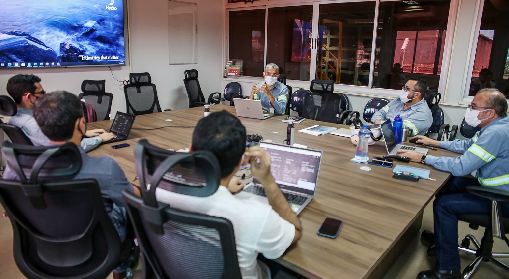 a group of people sitting around a table with laptops